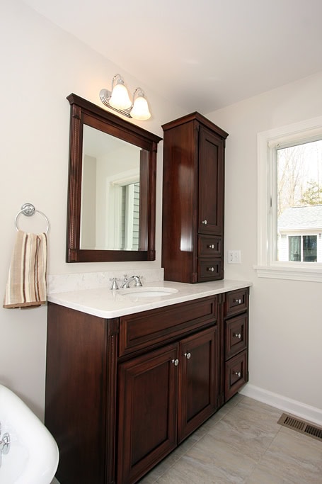 Bathroom vanity with dark wood cabinetry, mirror, and natural light from window.