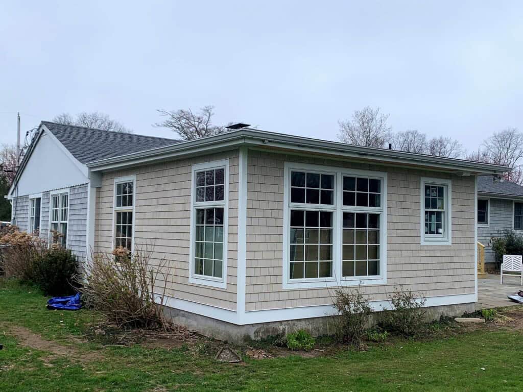 New home addition with large windows and modern design in a suburban setting.