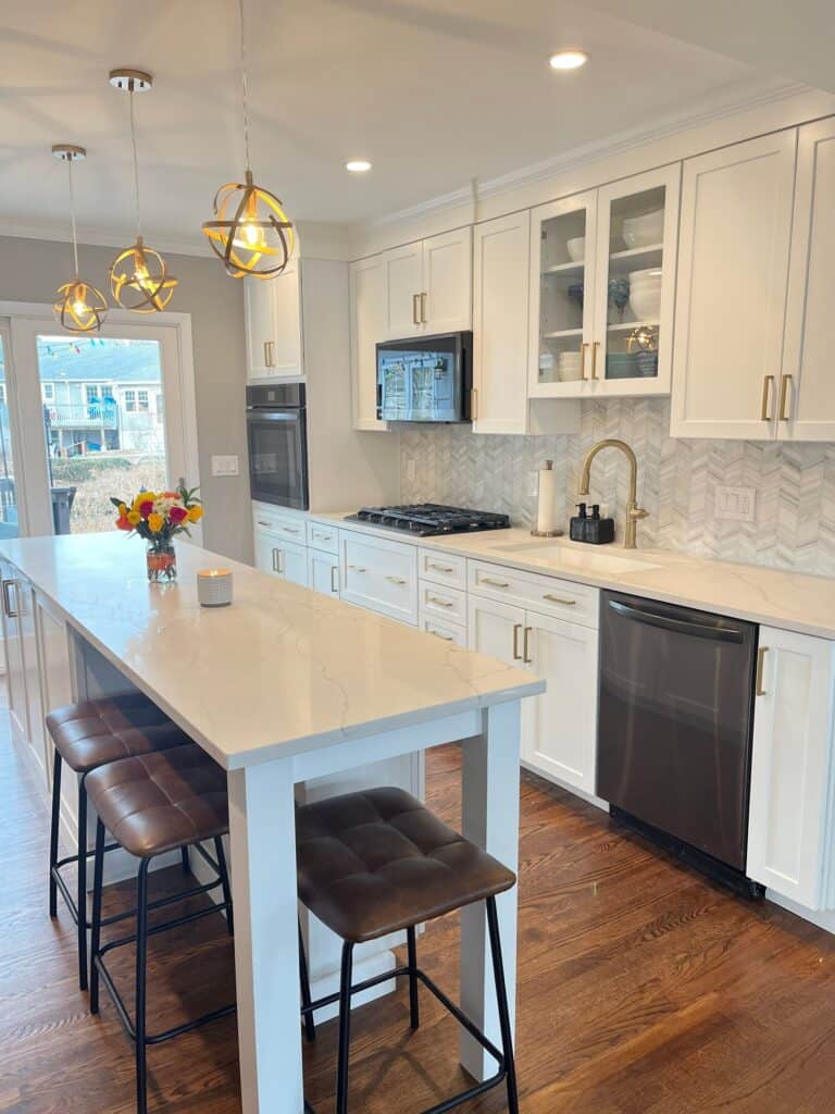 Bright modern kitchen with white cabinets, marble countertops, and stainless steel appliances.