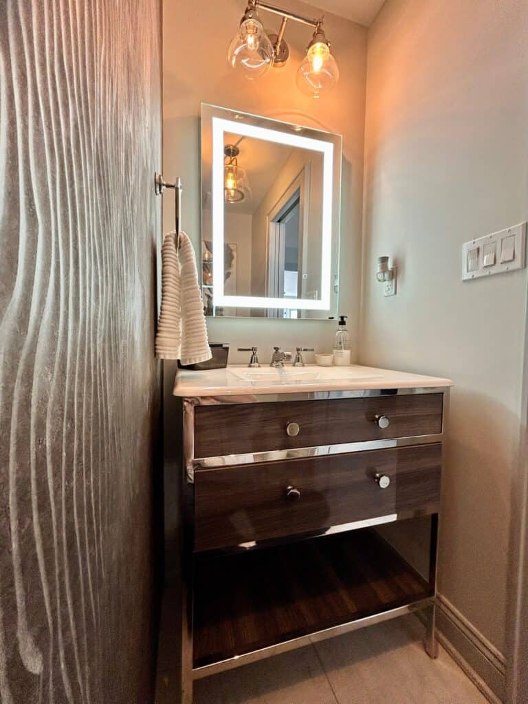Stylish bathroom vanity with illuminated mirror and contemporary lighting fixtures.