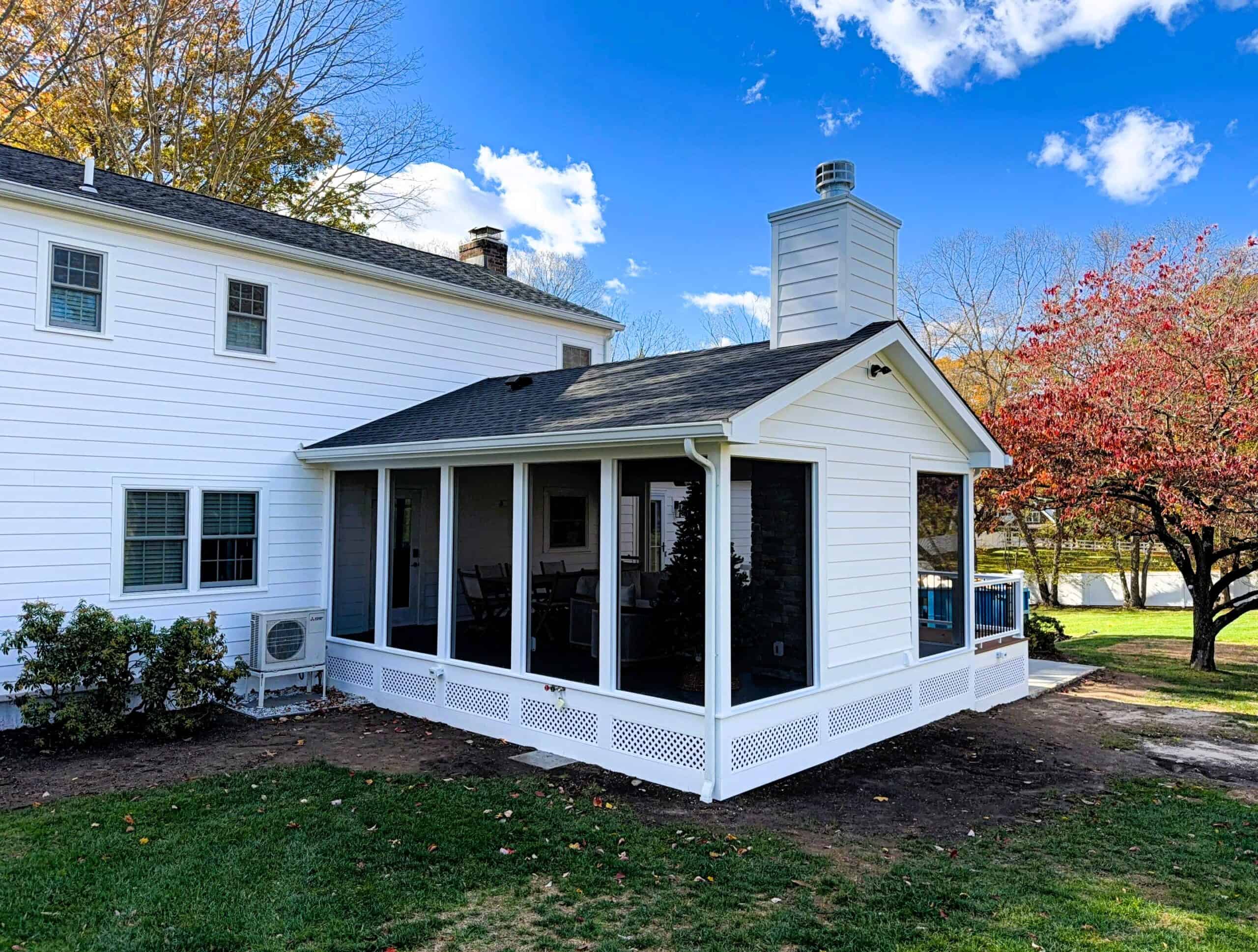 Sunroom addition with large screened windows and white siding.