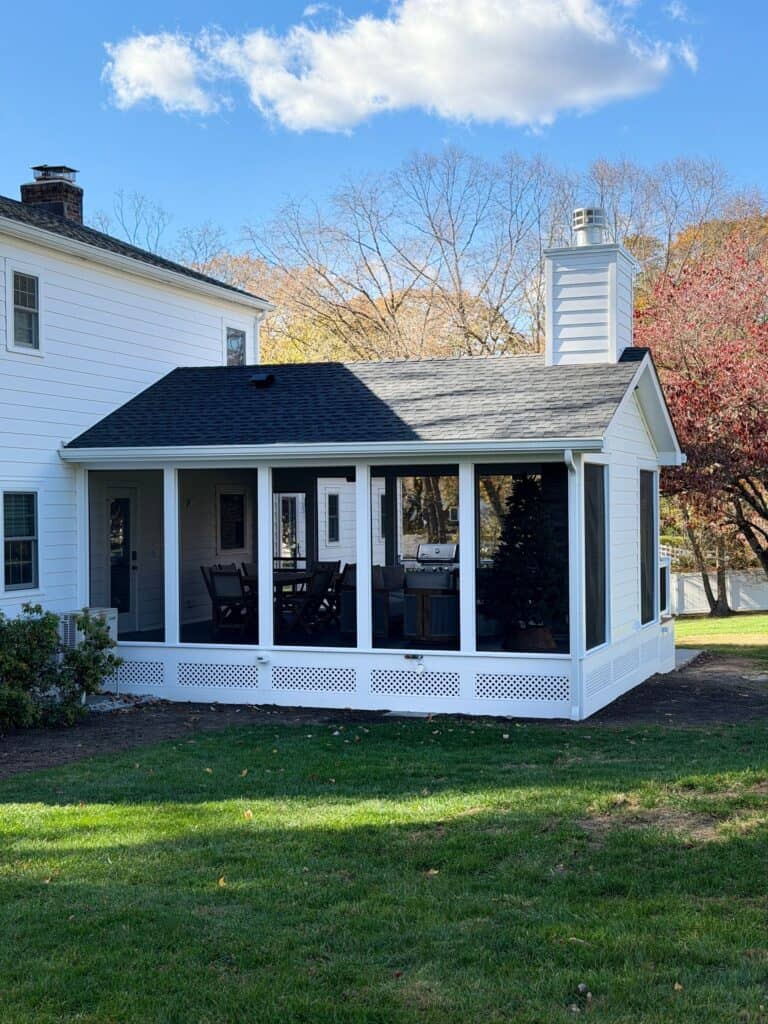 Sunroom addition with screened windows and outdoor seating.