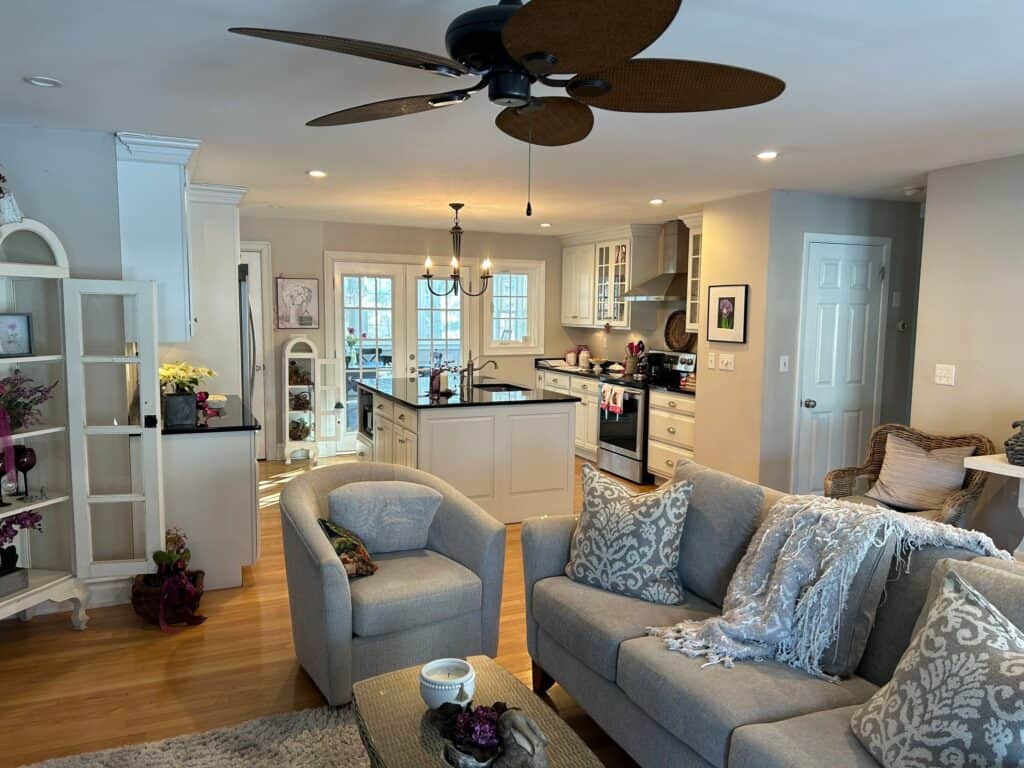 A welcoming living room featuring comfortable seating and a contemporary kitchen with white cabinets.