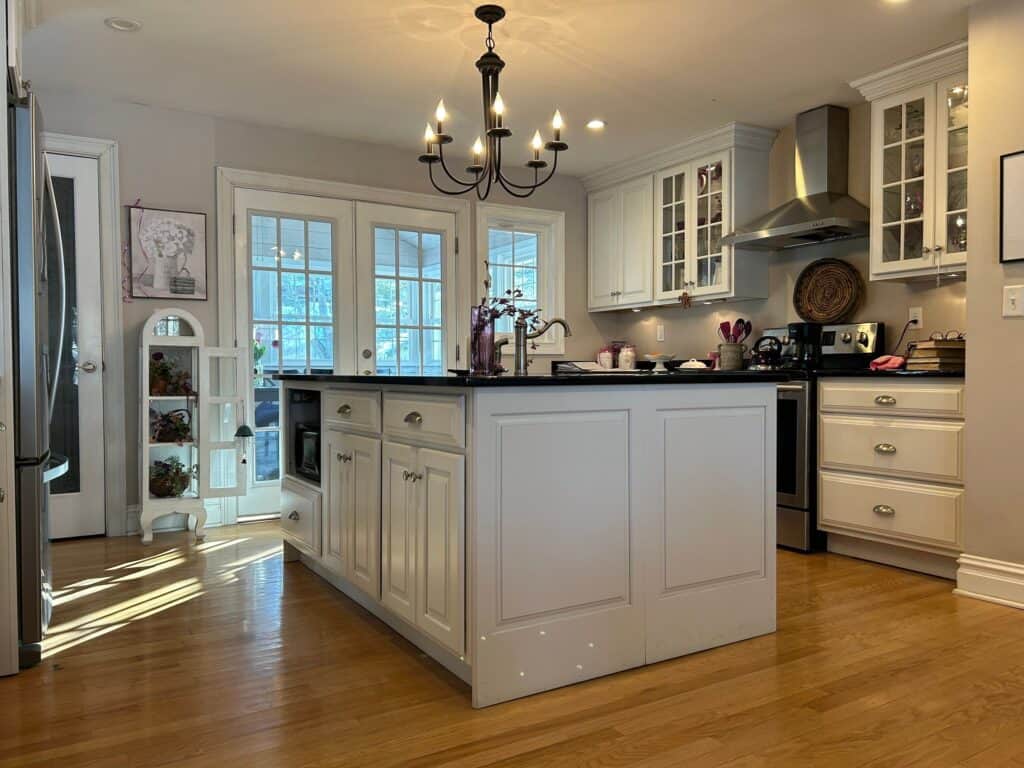 Bright modern kitchen with white cabinets, island, and stainless steel appliances.