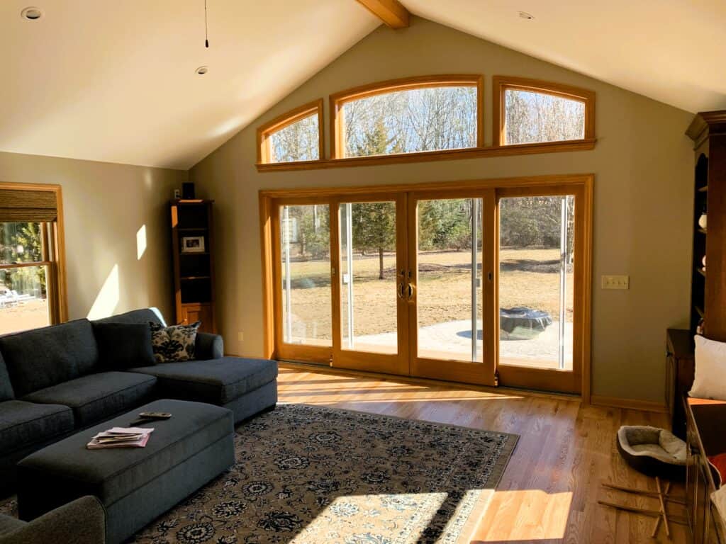 Bright living room with large glass doors and upper windows, offering natural light and scenic outdo.