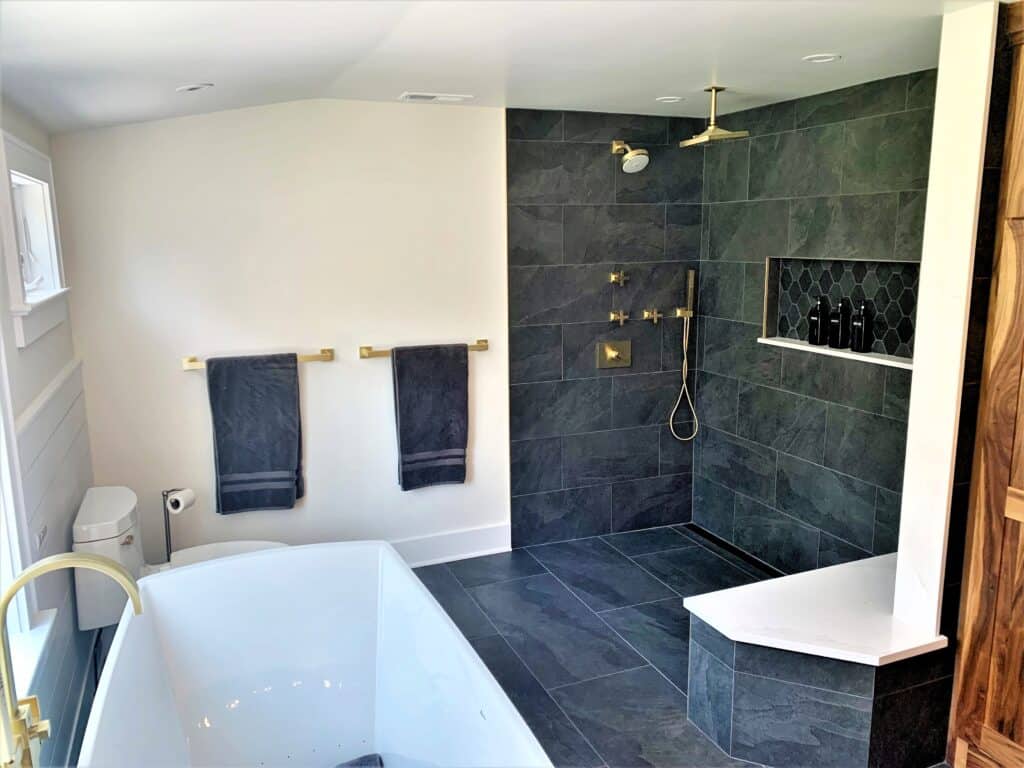 Elegant bathroom with a walk-in shower and freestanding bathtub, featuring dark tile accents and mod.