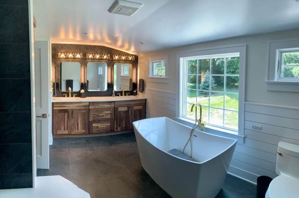 Elegant modern bathroom with a freestanding bathtub and dual vanity mirrors. Bright, spacious, and p.