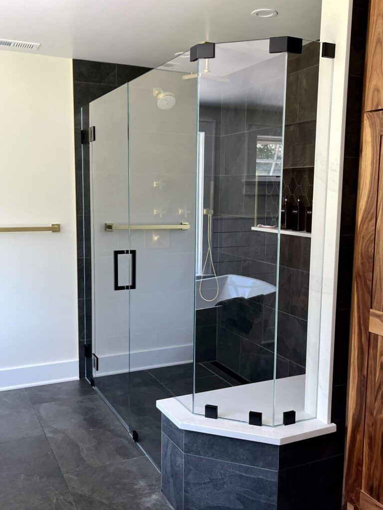 Elegant glass shower with black tile accents and a built-in bathtub.