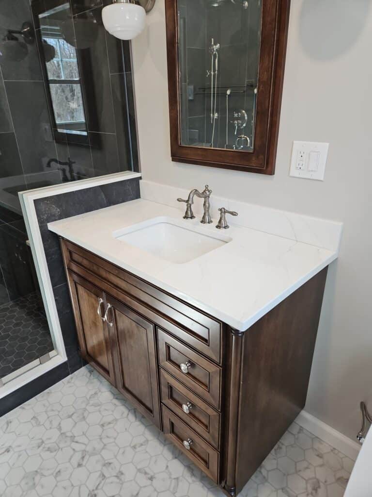 Elegant bathroom vanity with dark wood cabinet and white marble countertop.