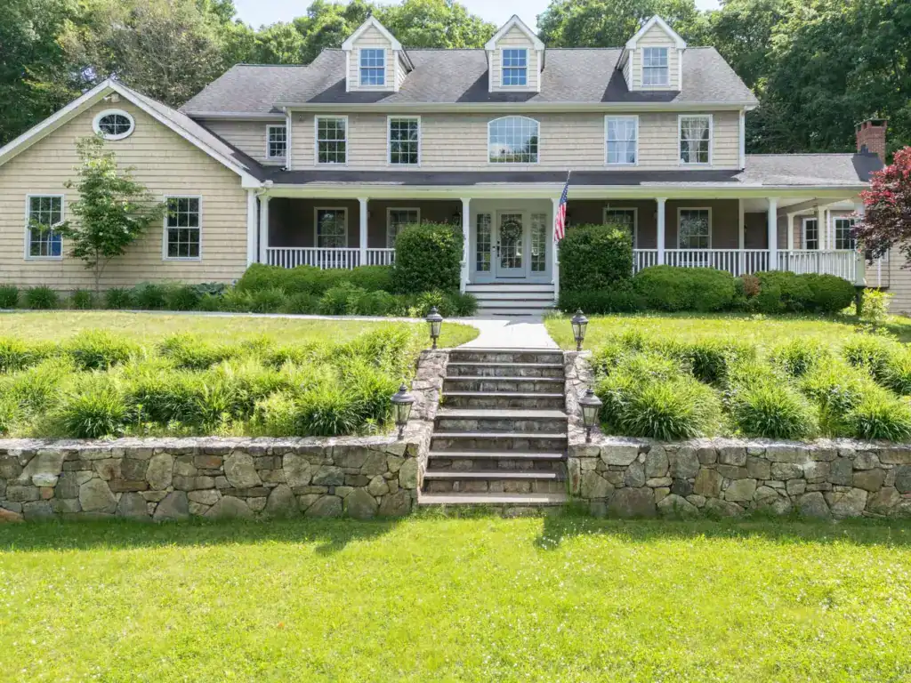 Beautiful two-story house with a spacious front porch and lush landscaping.
