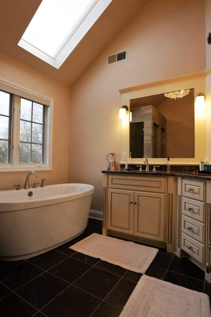 Elegant bathroom with a freestanding tub, vanity, and skylight for natural light.