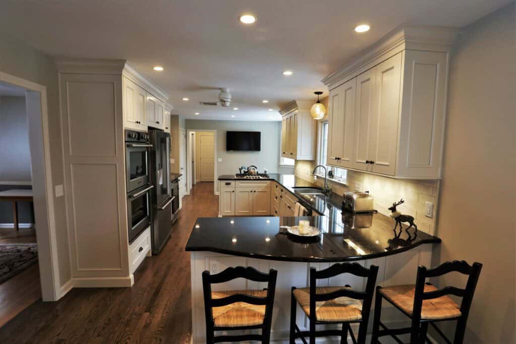 Spacious modern kitchen featuring white cabinetry, black granite countertops, and stainless steel ap.