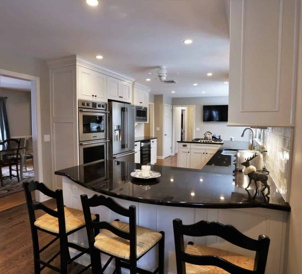 Modern kitchen with white cabinets, black countertops, and stainless steel appliances.