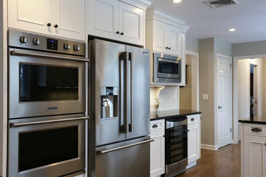 Contemporary kitchen featuring stainless steel refrigerator, oven, microwave, and white cabinetry.