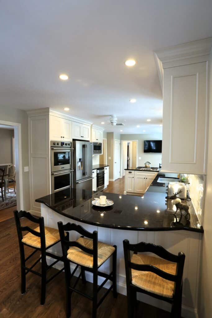 Bright modern kitchen with white cabinetry, black countertops, and stainless steel appliances.