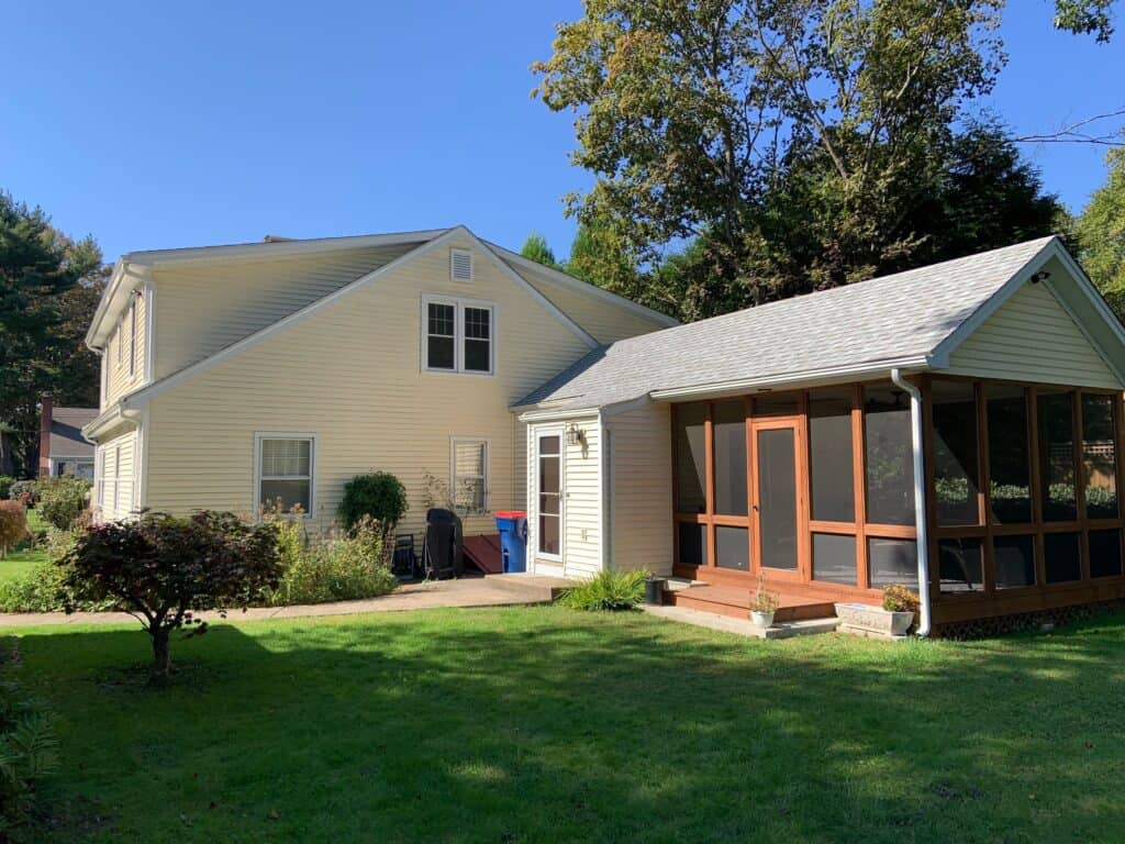 Beautiful home extension with screened porch and lush backyard landscaping.