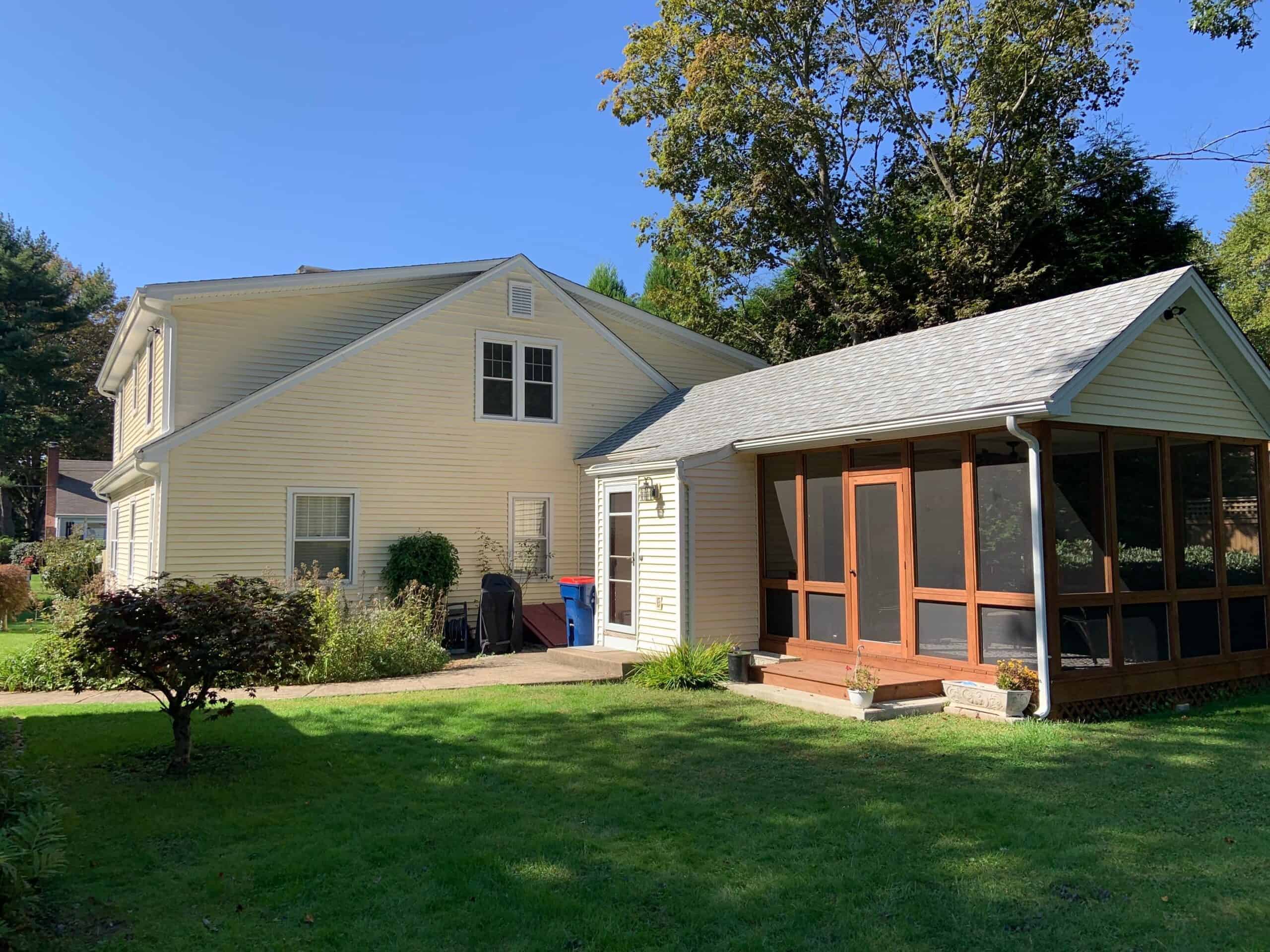 Beautiful home extension with screened porch and lush backyard landscaping.