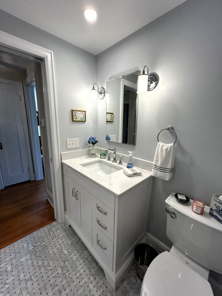 Bright bathroom with white vanity, mirror, and modern lighting fixtures.