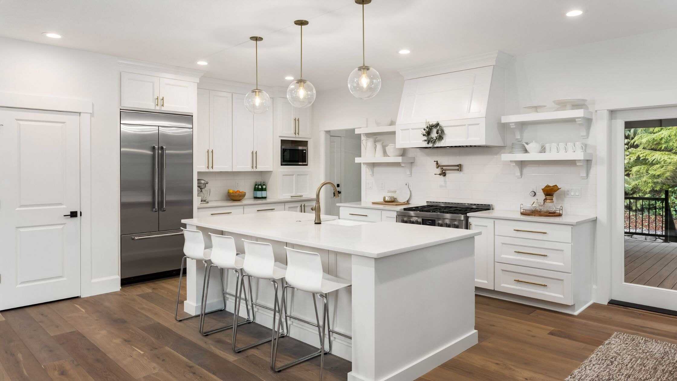 Bright modern white kitchen with island, stainless steel appliances, and ample storage.