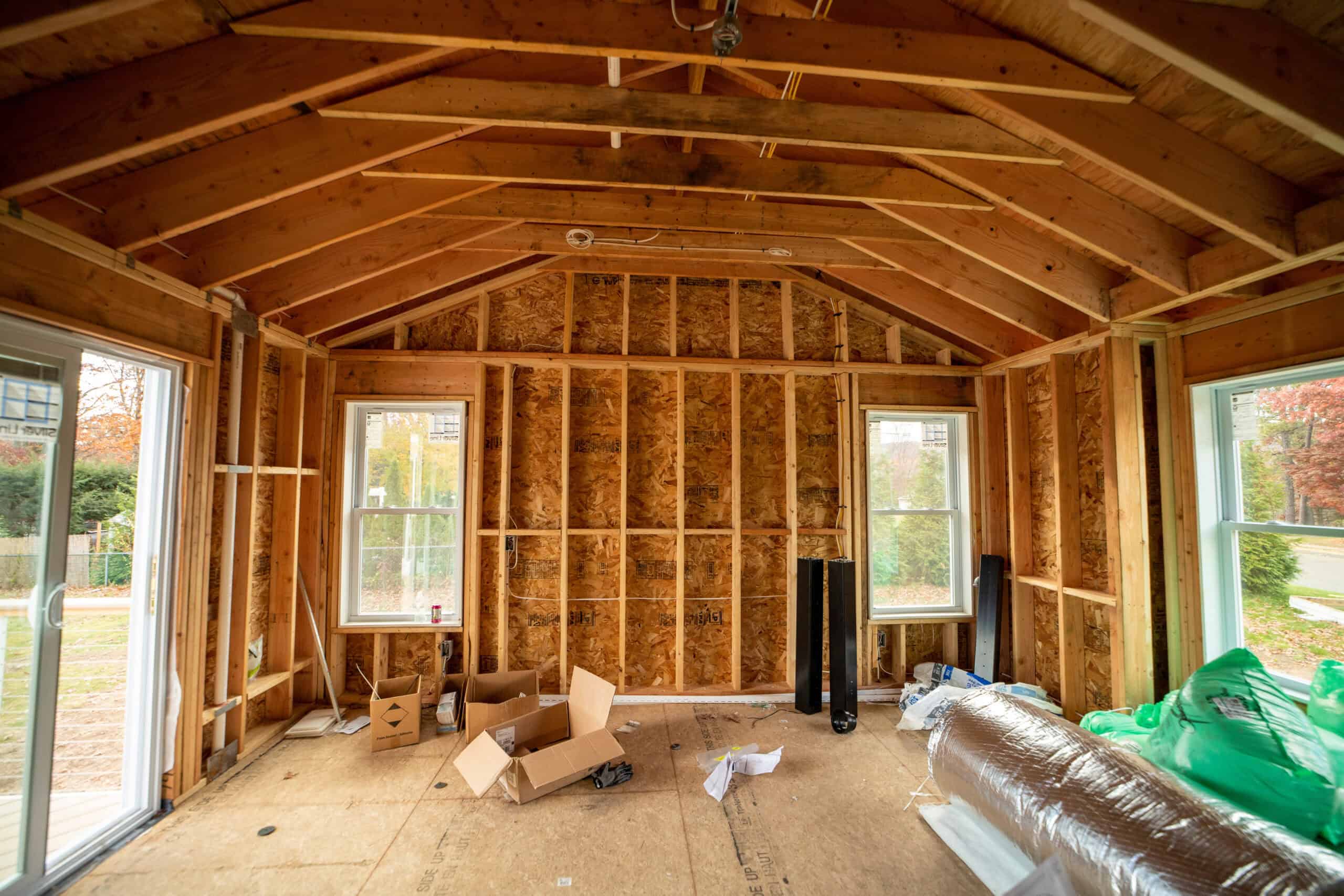 Interior framing of a house under construction with exposed wooden studs and roof trusses.