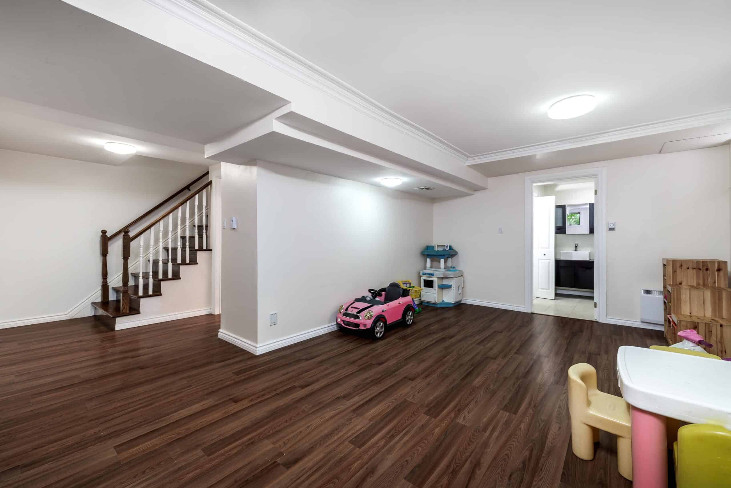 Spacious living room with wooden floors and children's toys.