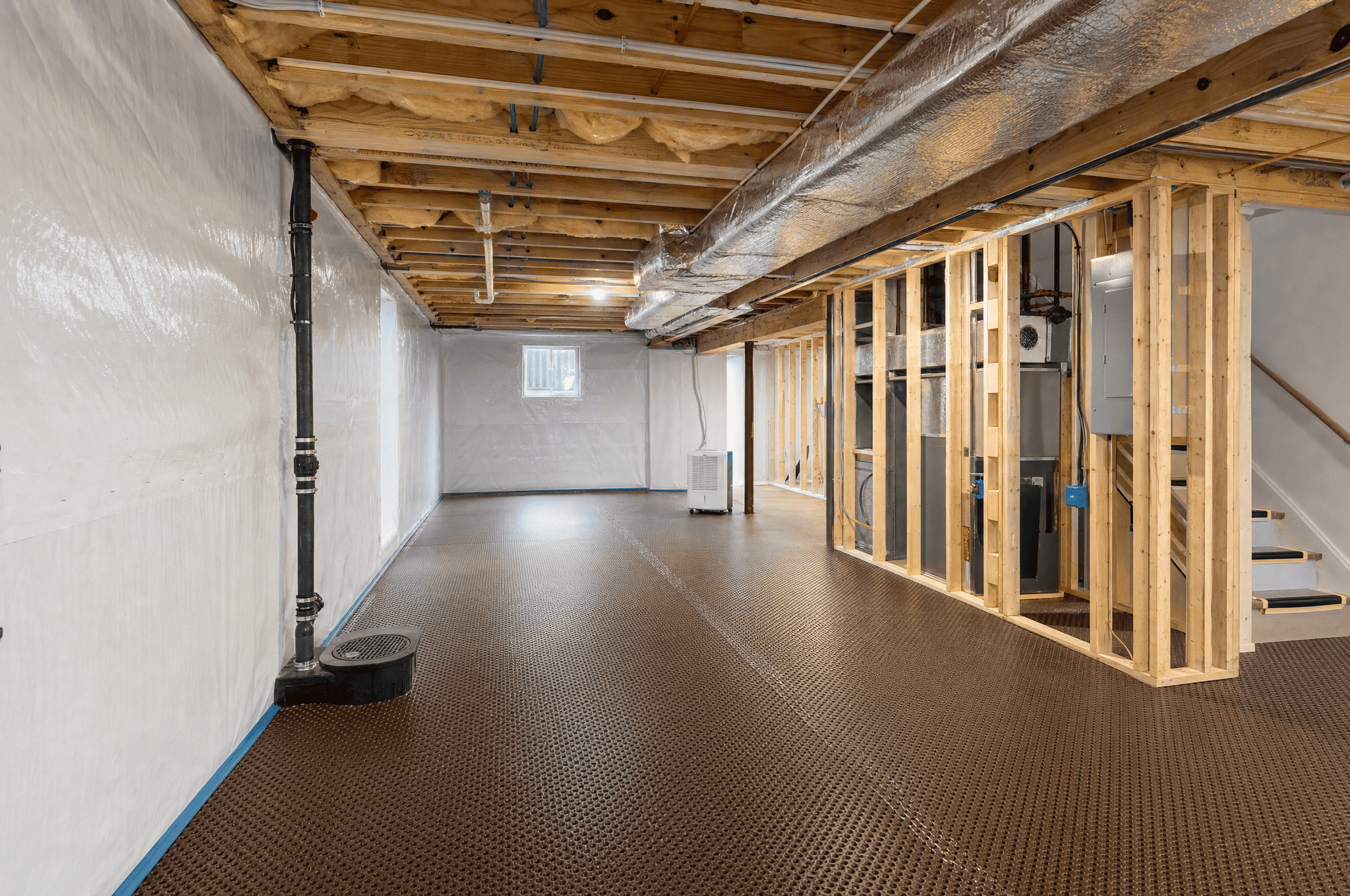 Unfinished basement with exposed framing and ductwork in progress.